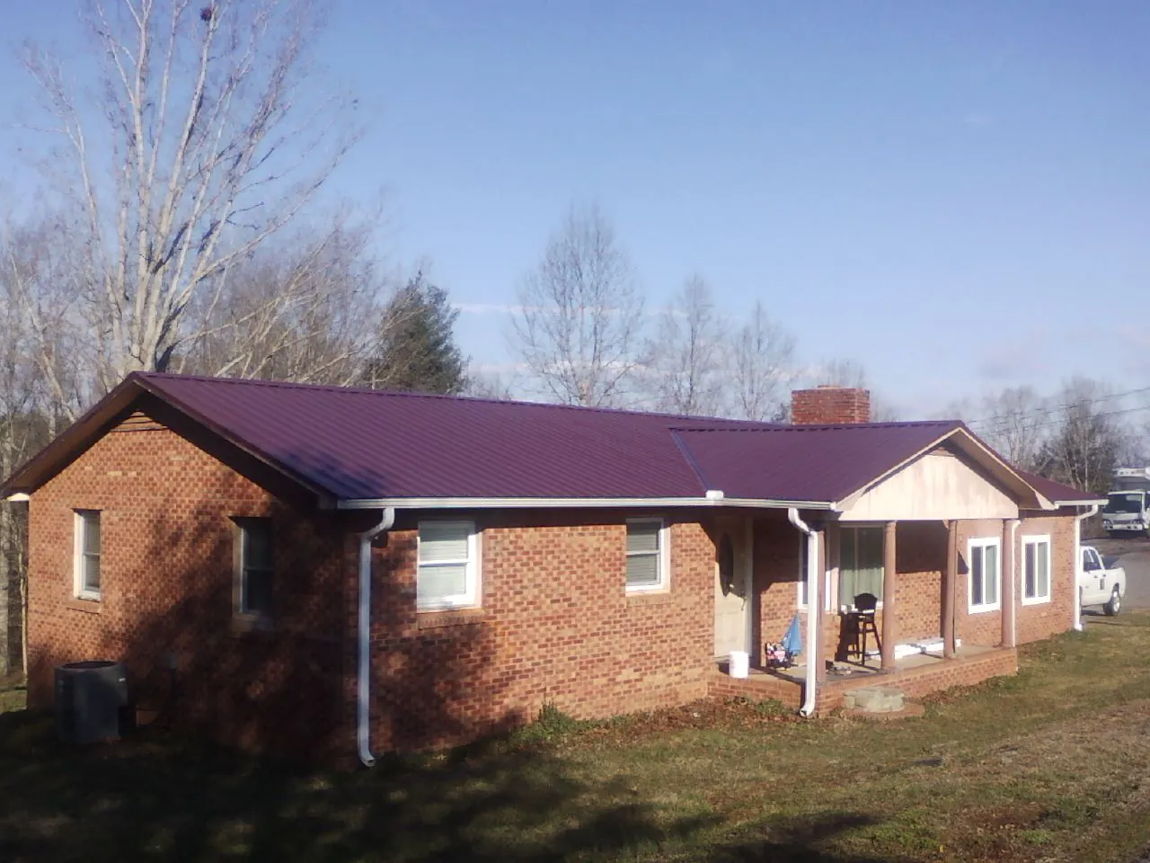 Burgundy metal roof on a brick ranch home with a new addition in Polaris
