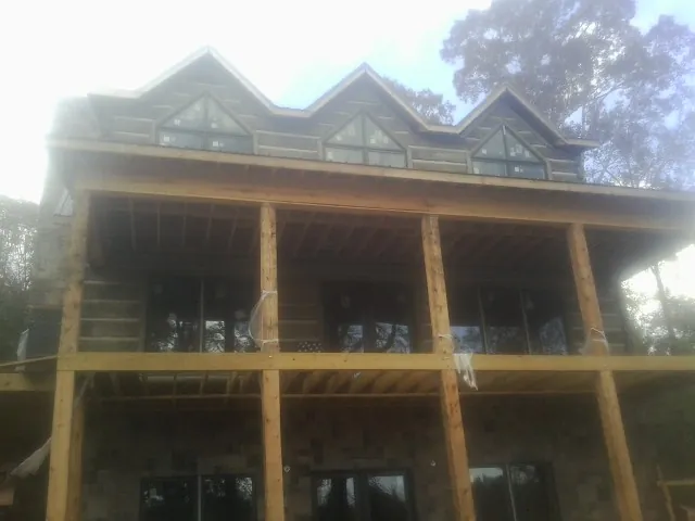 Dormers and porch framing on a large log home under construction — Roof Coating work by our crew in Polaris