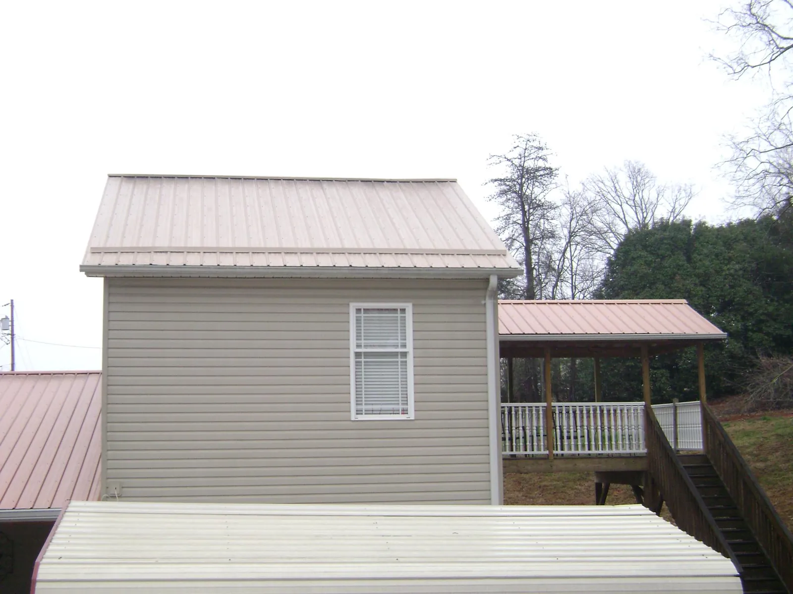 Tan metal roofs on a two story addition and attached porch, from a Roof Replacement job in Polaris