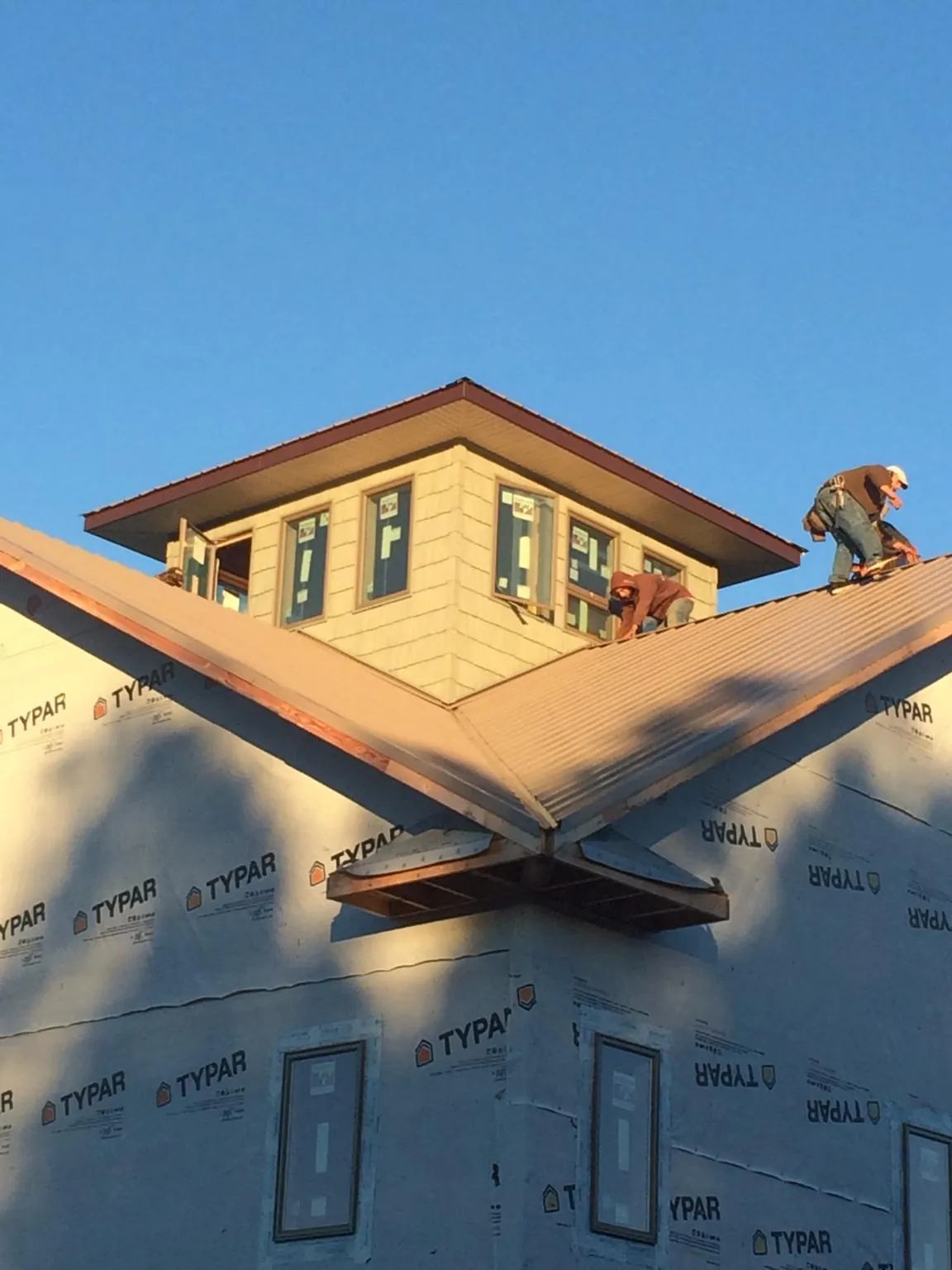 Roofers working around a rooftop cupola on a new metal roof at sunset — Roof Waterproofing in Polaris by Roofing Brothers